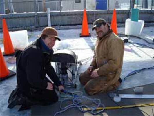 Scientist Dr. Jeremy Wilkinson, Scottish Association for Marine Science, left, and ERDC-CRREL's Bill Burch prepare the submersible trolley for testing within CRREL's Geophysical Research Facility. Attached to the trolley's structure are a suite of sensors that includes cameras, lasers and sonars, in an attempt to detect and map an oil spill from under the ice.