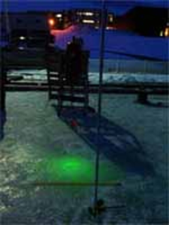 A beam of green light is emitted from the under ice laser during night testing. 