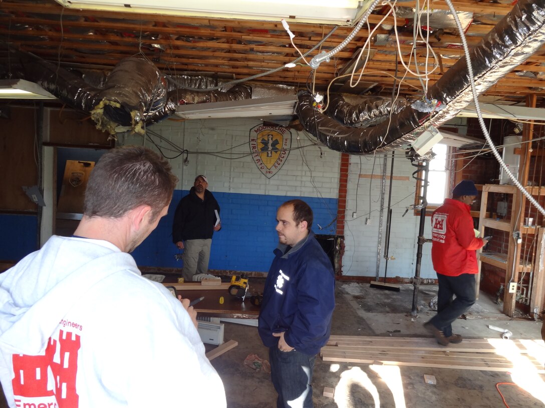 Simon Jackson (back to camera), cost estimator; Gian Garufo, project specialist for critical facilities, FEMA; Valdo Panzera, emergency medical technician, Moonachie First Aid and Rescue, and Gerald Deloach, electrical engineer, walk through the rescue squad’s headquarters to assess the need for temporary facilities for the squad after their building was flooded by Hurricane Sandy.