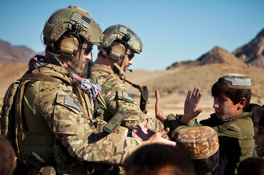 Coalition force members receive high fives from children in Farah province, Afghanistan, Dec. 11, 2012.