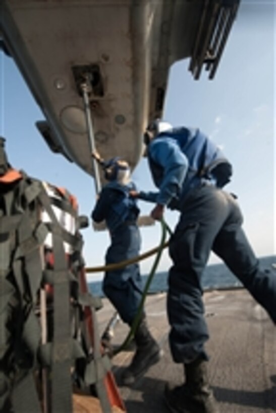 Seaman Samuel Soto, left, attaches a cargo pendant to an MH-60R Sea Hawk helicopter while Seaman Edward Johnson holds on to him as a safety observer during a vertical replenishment aboard the guided-missile cruiser USS Mobile Bay (CG 53) on Dec. 14, 2012.  The Mobile Bay is operating in the Arabian Sea as part of the John C. Stennis Carrier Strike Group.   The group is deployed to the 5th Fleet area of responsibility to conduct maritime security operations and theater security cooperation efforts.  