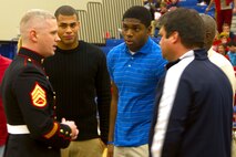 BROOKFIELD, Wis. - Staff Sergeant Kory Hampton congratulates Brookfield East senior Alec James and Brookfield Central senior Chikwe Obasih during halftime at the basketball game between the rival schools Dec. 18.  The two football players were selected to attend the second annual Semper Fidelis All-American Bowl, a nationally televised game that recognizes high-achieving high school student athletes. 