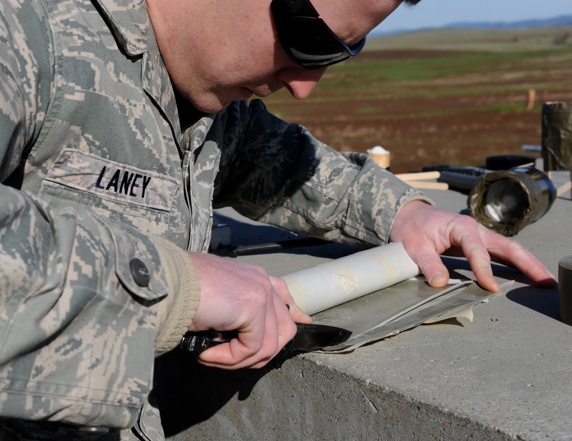 Staff Sgt. Robert Laney, 9th Civil Engineer Squadron explosive ordinance disposal technician, cuts a piece of plasticized explosive DATA sheet during a training scenario at the EOD range on Beale Air Force Base, Calif., Dec. 19, 2012. EOD Airmen train with different types of explosives to simulate what they may encounter in the field. (U.S. Air Force photo by Staff Sgt. Robert M. Trujillo/Released)