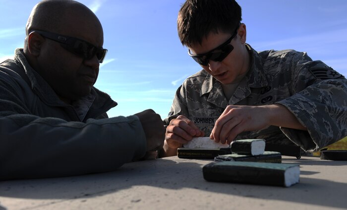 Tech. Sgt. Leonard Livas (left) and Staff Sgt. Daniel Johnsen, 9th Civil Engineer Squadron explosive ordnance disposal technicians, shape C4 explosives during a training scenario at the EOD range on Beale Air Force Base, Calif., Dec. 19, 2012. EOD Airmen train with different types of explosives to simulate what they may encounter in the field. (U.S. Air Force photo by Staff Sgt. Robert M. Trujillo/Released)
