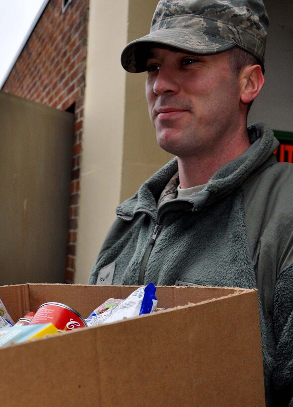 Airman 1st Class Kevin Clark from the 446th Aircraft Maintenance Squadron carries a Christmas basket to load into a van on Dec. 19 at the Central Pierce County Fire Department. The Christmas baskets will be delivered to the 446th Force Support Squadron Airman and Family Readiness Center where they will be picked up by families. (U.S. Air Force Photo/Airman 1st Class Madelyn McCullough)