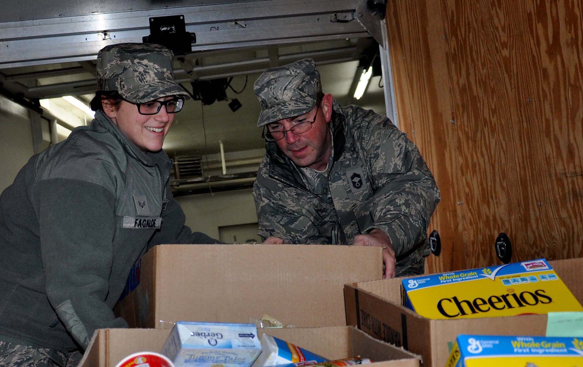 Senior Airman Sarah Fagalde from the 446th Aircraft Maintenance Squadron helps Chief Master Sgt. Chris Dietz from the 86th Aerial Port Squadron load a Christmas basket into the back of a van Dec. 19th at the Central Pierce County Fire Department. These Christmas baskets are a gift to 50 Reserve families at McChord Field. (U.S. Air Force Photo/Airman 1st Class Madelyn McCullough)