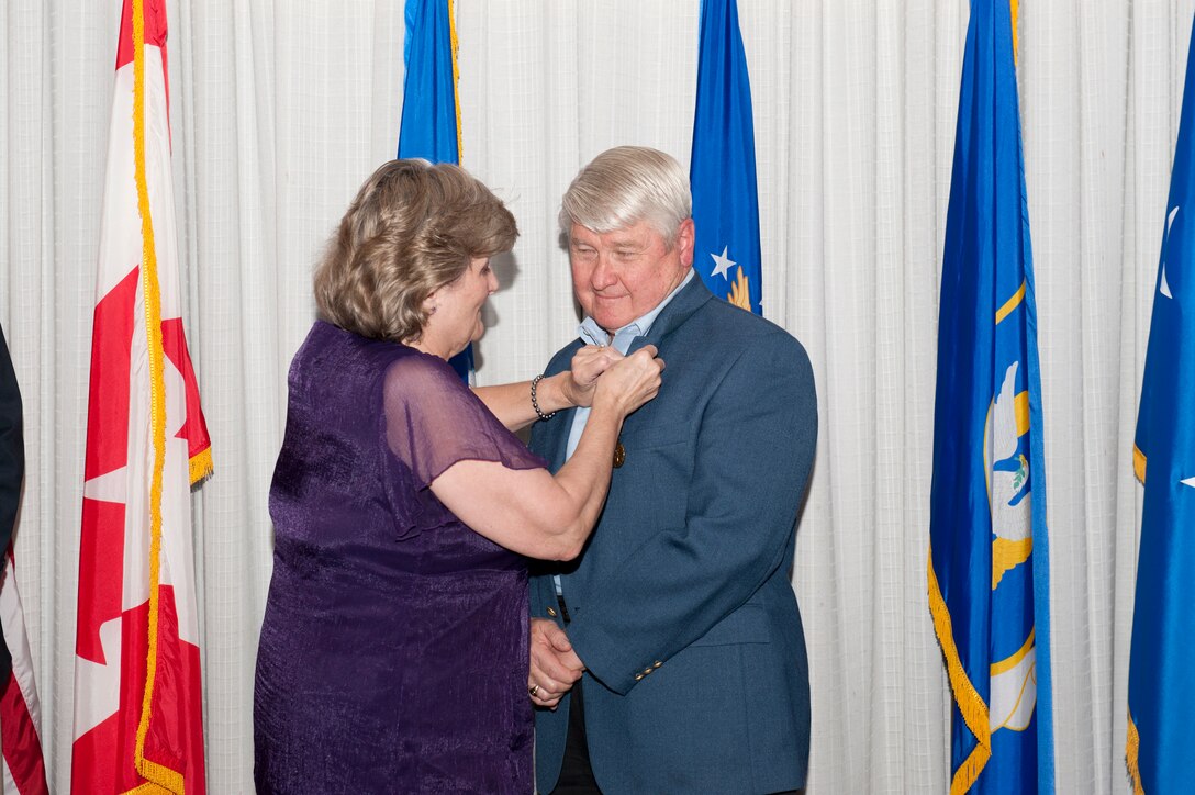 William 'Scotty' Scott's wife, Suzanne, fastens Scotty's retirement pin on his lapel during his retirement dinner December 13. Prior to his retirement, Scotty had a combined active-duty Air Force and federal service career that spanned 43 years. (Air Force photo by Lisa Norman)