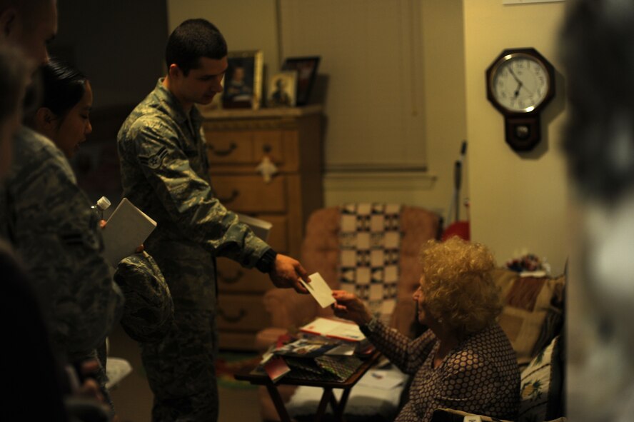 Airman 1st Class Emmett Unbehagen, a cyber-system operator of 1st Special Operations Communications Squadron, center left, hands a holiday card to a resident of the Hawthorn House during a card delivery at the Air Force Enlisted Village in Shalimar, Fla., Dec. 19, 2012. Unbehagen, also outreach liaison for Hurlburt Airman's Voice, coordinated with Airmen Committed to Excellence at Kunsan Air Base, Republic of Korea, to sign, seal and deliver the cards to the widows of the village. (U.S. Air Force photo / Senior Airman Joe McFadden)