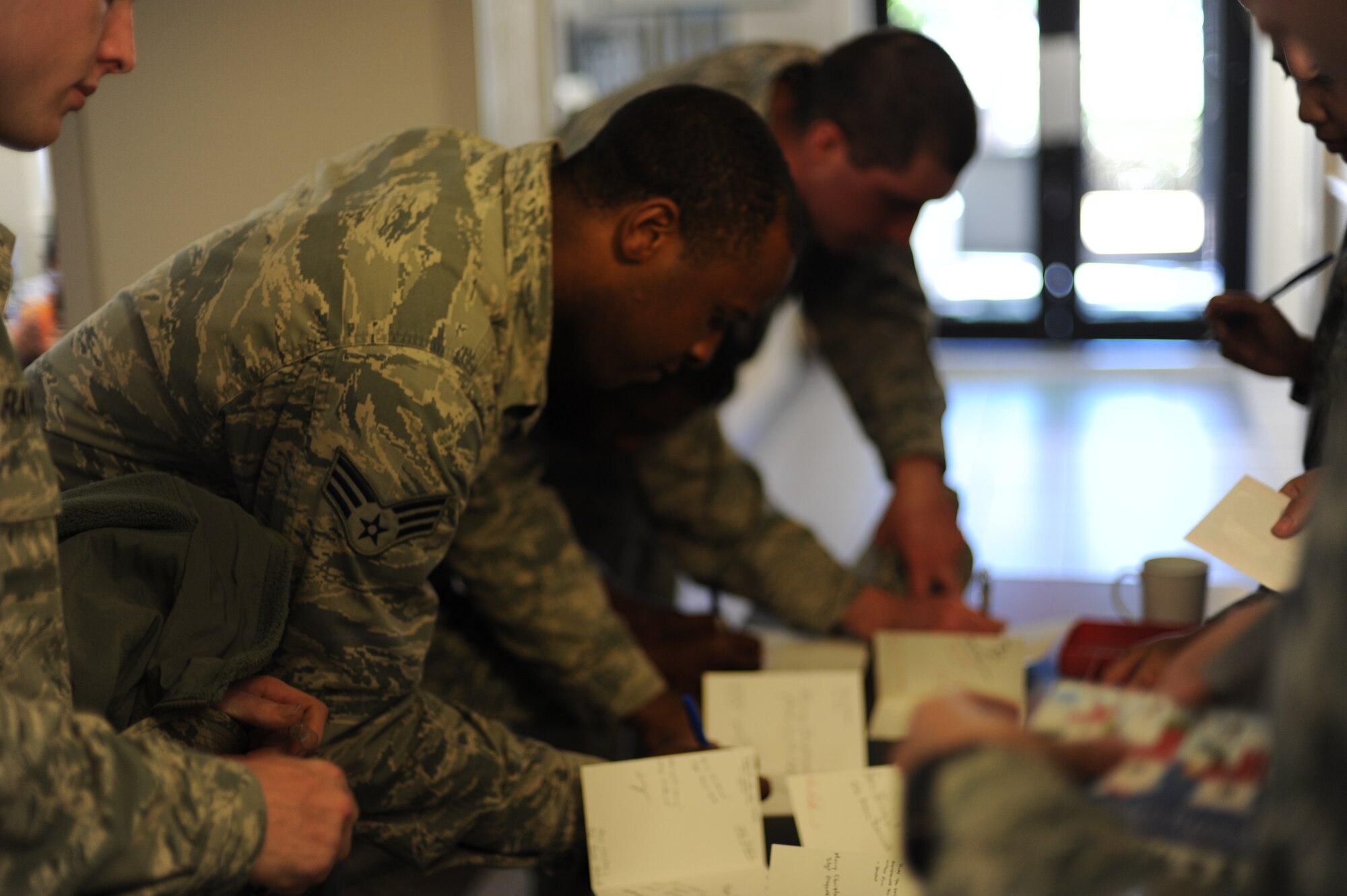 Hurlburt Airmen gather to sign holiday cards while at the Reef Dining Facility at Hurlburt Field, Fla., Dec. 19, 2012. The cards originally came from Airmen at Kunsan Air Base, Korea, and were later delivered to the widows of the Air Force Enlisted Village in Shalimar, Fla. (U.S. Air Force photo / Senior Airman Joe McFadden)