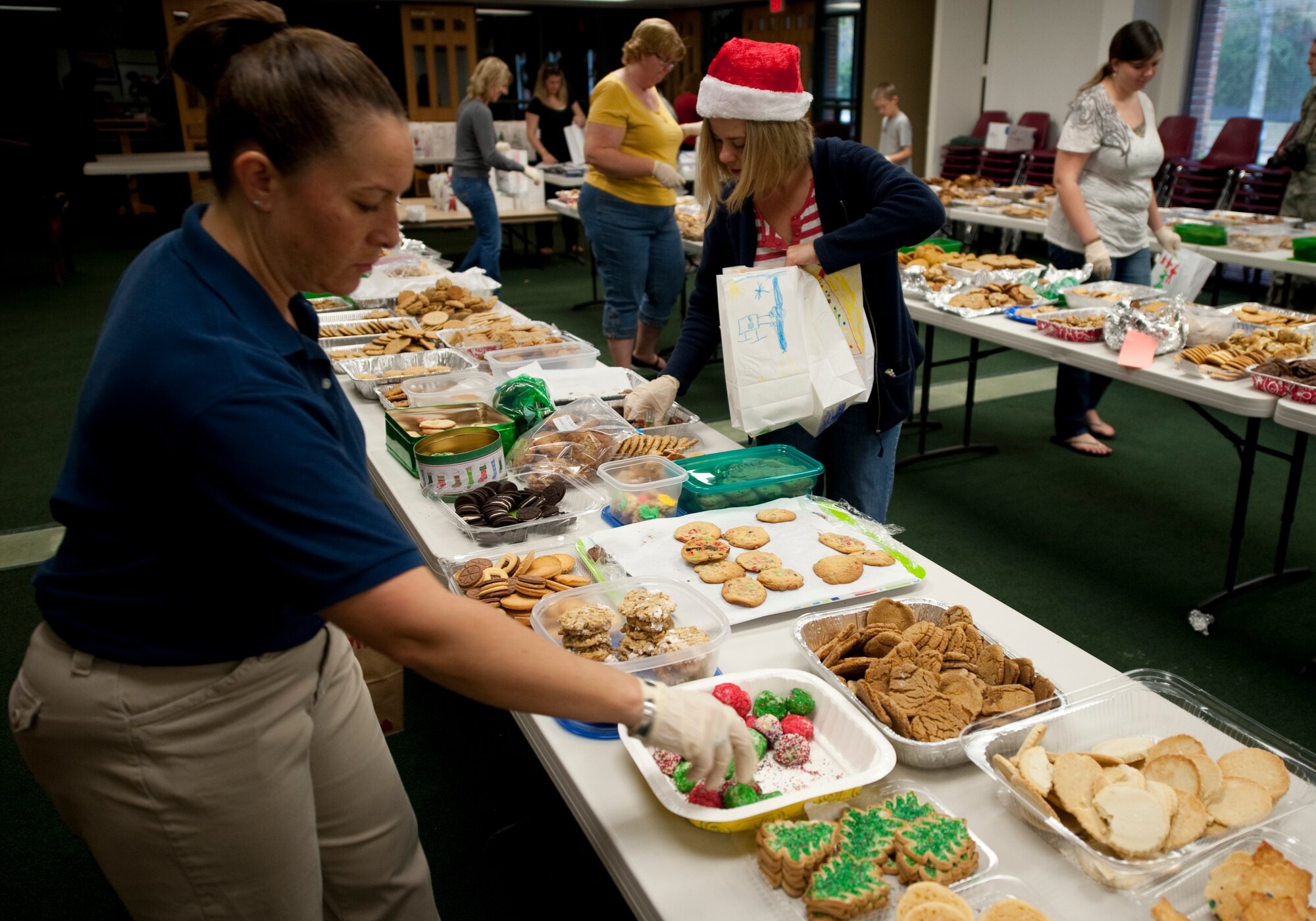 Volunteers from the Hurlburt Spouses Club pick cookies from more than a dozen assortments of baked goods to place in decorated paper bags during preparations for the annual Commando Cookie Drop on Hurlburt Field, Fla., Dec. 17, 2012. Volunteers divided more than 15,000 cookies into approximately 1,200 bags to be presented to single Airmen who live in the on-base dormitories.  (U.S. photo by Senior Airman Kentavist P. Brackin)