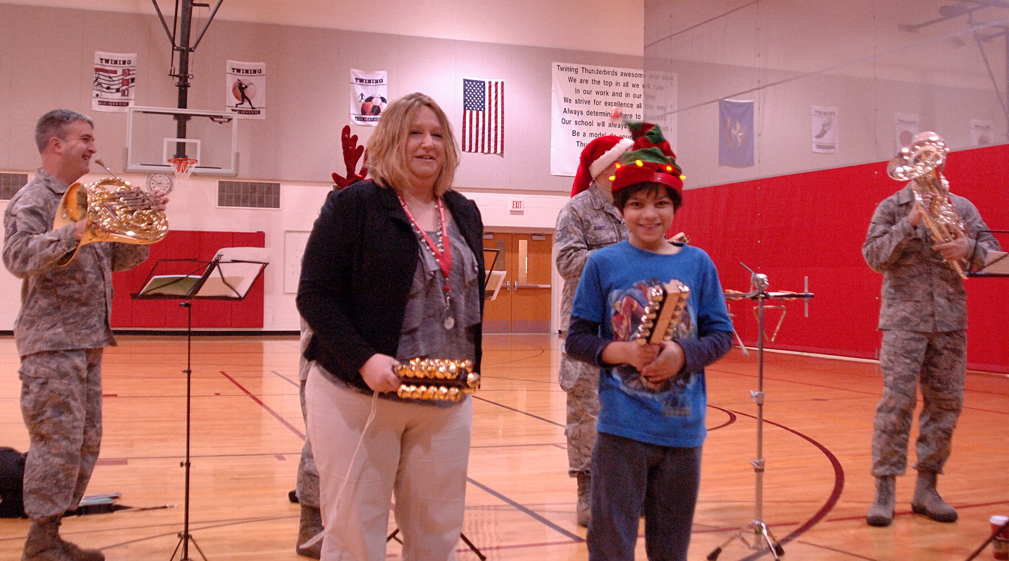 Angie Emmons, a paraprofessional at Nathan Twinning Elementary/Middle School and Sam Chavez, play the sleigh bells with the United States Air Force Heartland of America Band Dec. 19, 2012, on Grand Forks Air Force Base, N.D. The band toured the base for two consecutive days, performing 22 times. (U.S. Air Force photo/Airman 1st Class Zachiah Roberson)