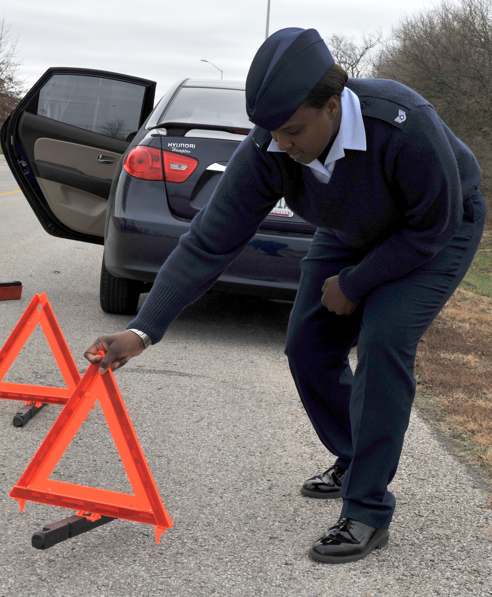 Staff Sgt. Fatimat Bello, 509th Bomb Wing Ground Safety, takes safety precaution and sets a highway warning triangle to notify on-coming traffic Dec. 10 at Whiteman Air Force Base, Mo. Team Whiteman is encouraged to take precautions, travel with a safety kit and be prepared at all times in case an emergency arises. (U.S. Air Force photo/Heidi Hunt) (Released) 