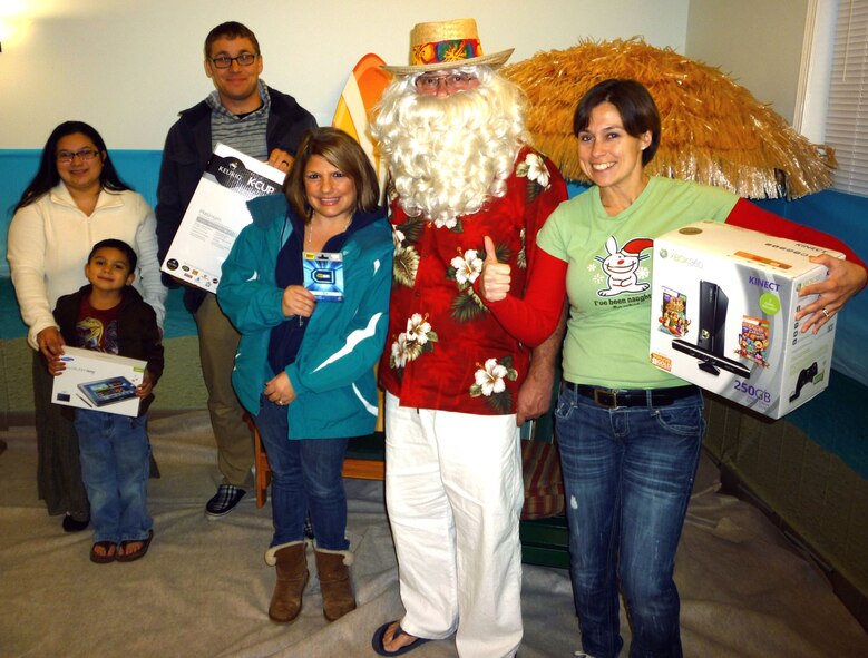 HANSCOM AIR FORCE BASE, Mass. – Winners of the CEL survey drawing pose with their prizes and Hawaiian Santa during Hanscom Family Housing’s Hawaiian Christmas Social at the community center Dec. 12. Attendees were treated to tropical-themed refreshments and fun. (Courtesy photo)