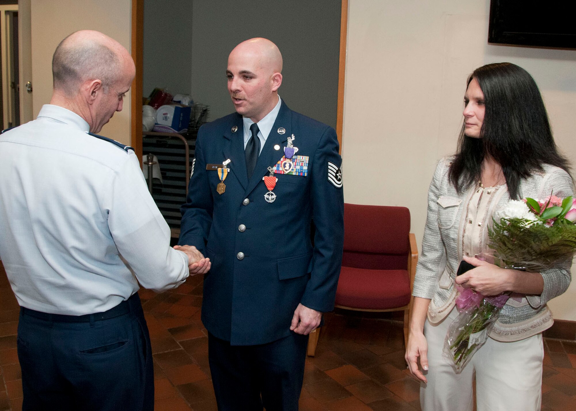 HANSCOM AIR FORCE BASE, Mass. -- Col. Lester A. Weilacher, 66th Air Base Group commander, congratulates recently retired Tech. Sgt. Patrick T. Ryan Jr. and his wife, Holly, after a ceremony in the O'Neill Auditorium Dec. 14. During his retirement ceremony, Ryan received the Purple Heart Medal for injuries received during a deployment to Iraq and the Combat Action Medal for engaging the enemy 10 days later. (U.S. Air Force photo by Mark Wyatt)
