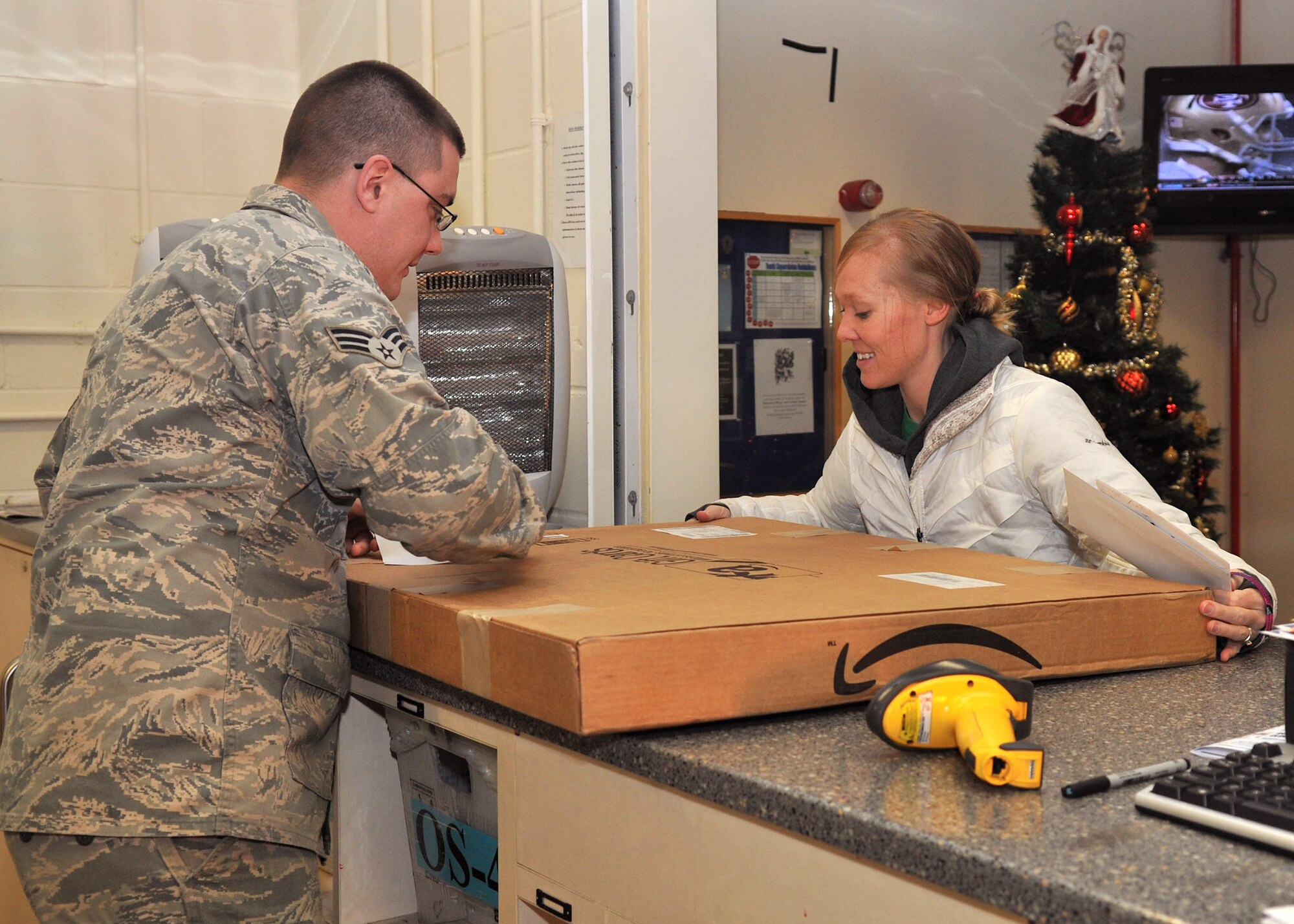 Senior Airman Casey Jackson, 100th Maintenance Squadron hydraulics apprentice from Columbus, Ohio, assists a customer Dec. 19, 2012, at the base post office at RAF Mildenhall, England. Jackson was one of more than 60 Airmen around the base who volunteered at the post office to assist with the added workload during the holiday season. (U.S. Air Force photo by Senior Airman Jerilyn Quintanilla/Released)