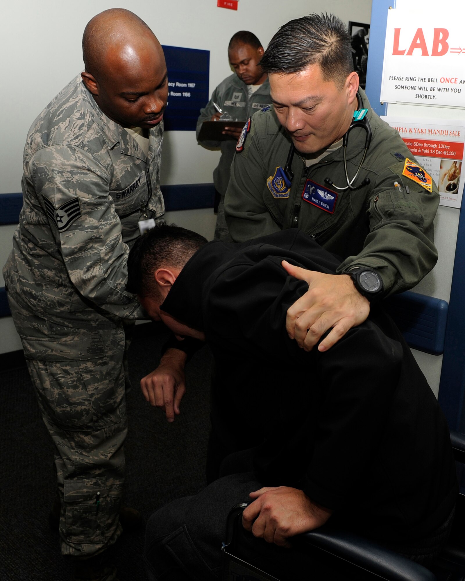 Staff Sgt. Mohamed Swarray, left, 8th Medical Support Squadron, and Lt. Col. Naili Chen, 8th Medical Operations Squadron commander, assist a patient into a wheelchair on  Kunsan Air Base, Republic of Korea, Dec 11, 2012. The patient was part of a training exercise to see how medical personnel respond to an emergency. (U.S. Air Force photo by Senior Airman Marcus Morris/released)