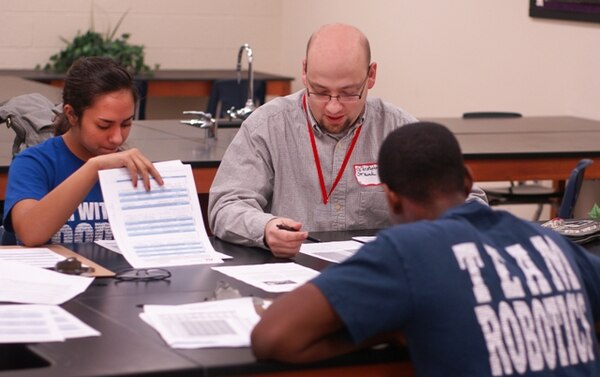 Chris Strunk, Tulsa District USACE Dam Safety Production Center, Chief of Dam and Levee Design Section confers with members of one of the robotics teams at the Tulsa FIRST LEGO League qualifying event Nov. 10. Strunk participated in the event as a judge and mentor as part of the USACE Science, Technology, Engineering and Mathematics (STEM) outreach program.