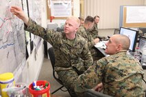 Second Lt. Evan C. Malone, the watch officer for 2nd Supply Battalion, 2nd Marine Logistics Group’s combat operations center training exercise aboard Camp Johnson, N.C., examines a map of his unit’s area of operations Dec. 19, 2012. The unit incorporated computer simulators into the training, which allowed Malone and other Marines to gather real-time information for their command decisions in the COC.