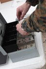 Staff Sgt. Donald W. Tubbs, a morale, welfare, recreation specialist with Combat Logistics Regiment 27, 2nd Marine Logistics Group, provides change for a purchase made from a Warfighter Express Services Team established at Onlsow Beach aboard Camp Lejeune, N.C., Dec. 18, 2012. Tubbs returned to the beach daily to sell small commodities such as snacks and drinks to the Marines and sailors while they worked in the field.