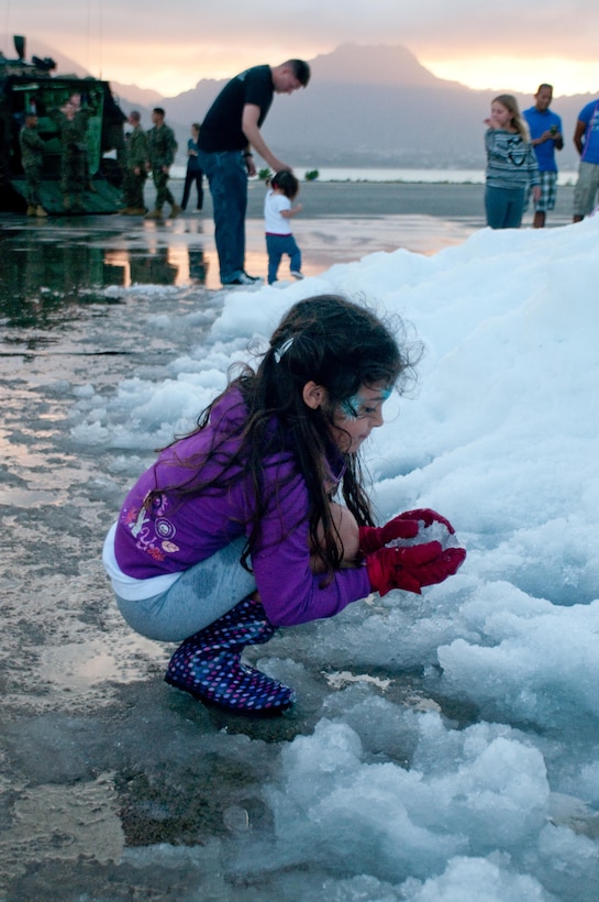MARINE CORPS BASE HAWAII - Iolana Nuzzo, 7, packs a snowball outside Hangar 101 and enjoys the manmade snow available at 3rd Marine Regiment’s holiday party, Dec. 13, 2012. Nuzzo and other children playing in the snow were also able to ride in tactical vehicles and visit with Santa. (Official U.S. Marine Corps photo by Christine Cabalo)