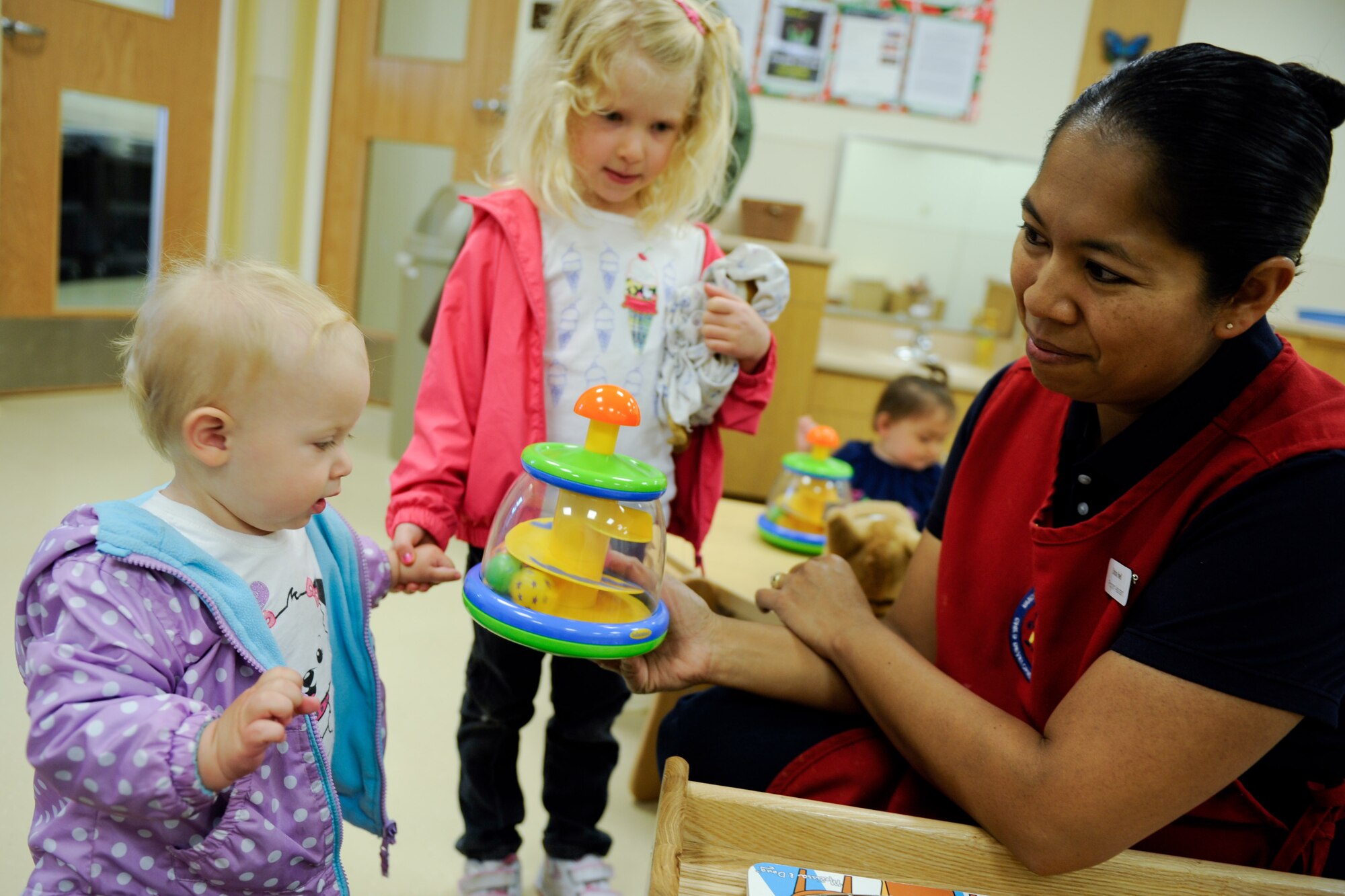 VANDENBERG AIR FORCE BASE, Calif. -- Lexie Korby and her older sister, Allie Korby, both daughters of Maj. Jennifer Korby, the 614th Air Operations Center director of staff, play with Cristina Powell, a Child Development Center program assistant, before Lexie is left at the new CDC here Wednesday, May 23, 2012. The new CDC opened for business Monday and has the capacity to provide care for 172 children. (U.S. Air Force photo/Staff Sgt. Levi Riendeau)