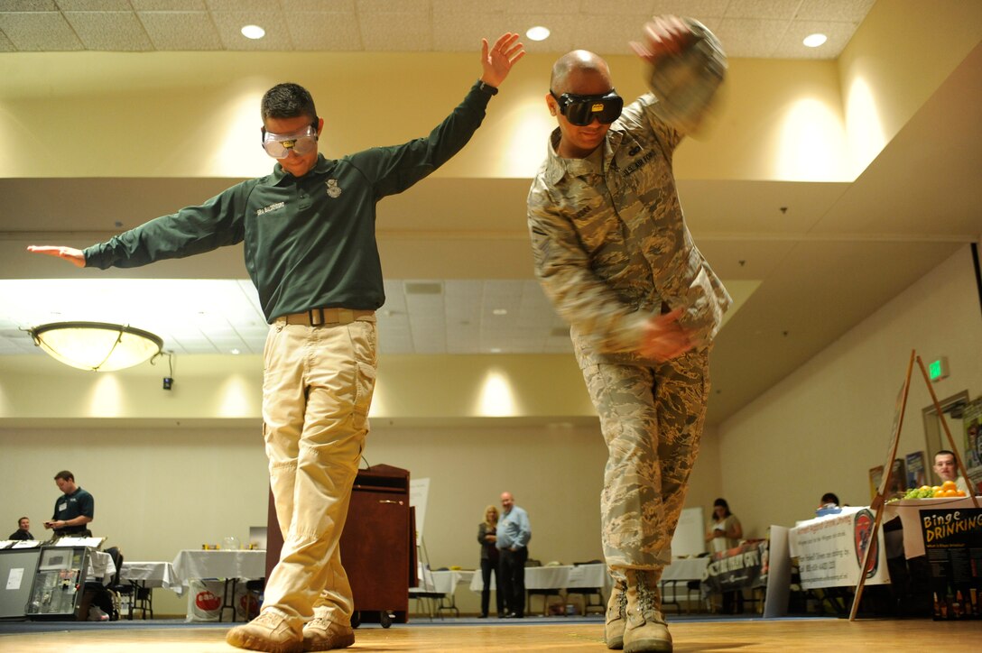 VANDENBERG AIR FORCE BASE, Calif. -- Senior Airman Zachary Baldenegro, 30th Security Forces Squadron conservation law enforcement officer, and Master Sgt. Bradford Cambra, 30th Space Wing Wing Staff Agencies and Comptroller Squadron first sergeant, walk a line using vision impaired goggles during a safety expo at the Pacific Coast Club here Wednesday, May 23, 2012. Multiple organizations participated in the expo to show safety equipment and services they provide on and off base. (U.S. Air Force photo/Staff Sgt. Andrew Satran) 