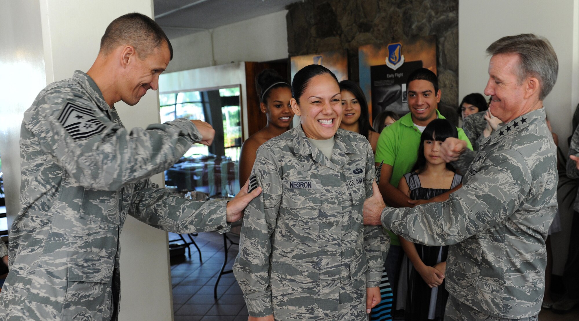Chief Master Sgt. Steve McDonald, Pacific Air Forces command chief (left) and Gen. Herbert "Hawk" Carlisle, PACAF commander (right), tacks technical sergeant stripes on a surprised Staff Sgt. Kristy Lynn Negron, non-commissioned officer in charge of PACAF Executive Services (middle), during the command’s holiday party at PACAF Headquarters, Hawaii, Dec. 20. 2012. Negron was recognized for her outstanding contributions to the mission through hard work and determination.  (U.S. Air Force photo/Tech. Sgt. Jerome S. Tayborn/Released)