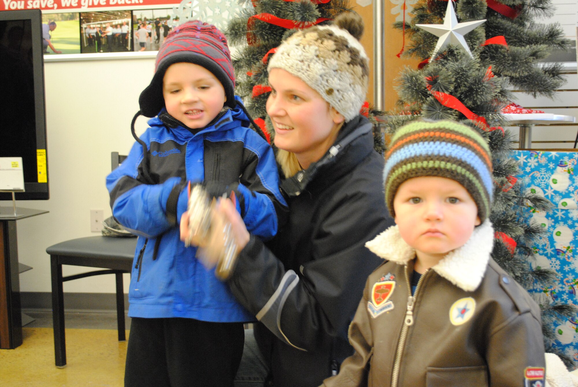 Cami Moberg, wife of Capt. (Dr.) Matthew Moberg, helps her four-year-old son, Blaise, play the sleigh bell while one-year-old Judson curiously looks at the members of the United States Air Force Heartland of America Band, play “Jingle Bells,” Dec. 18, 2012, at the Exchange on Grand Forks Air Force Base, N.D. The band toured the base for two consecutive days, performing holiday songs at 22 locations around the base. (U.S. Air Force photo/Senior Airman Luis Loza Gutierrez)