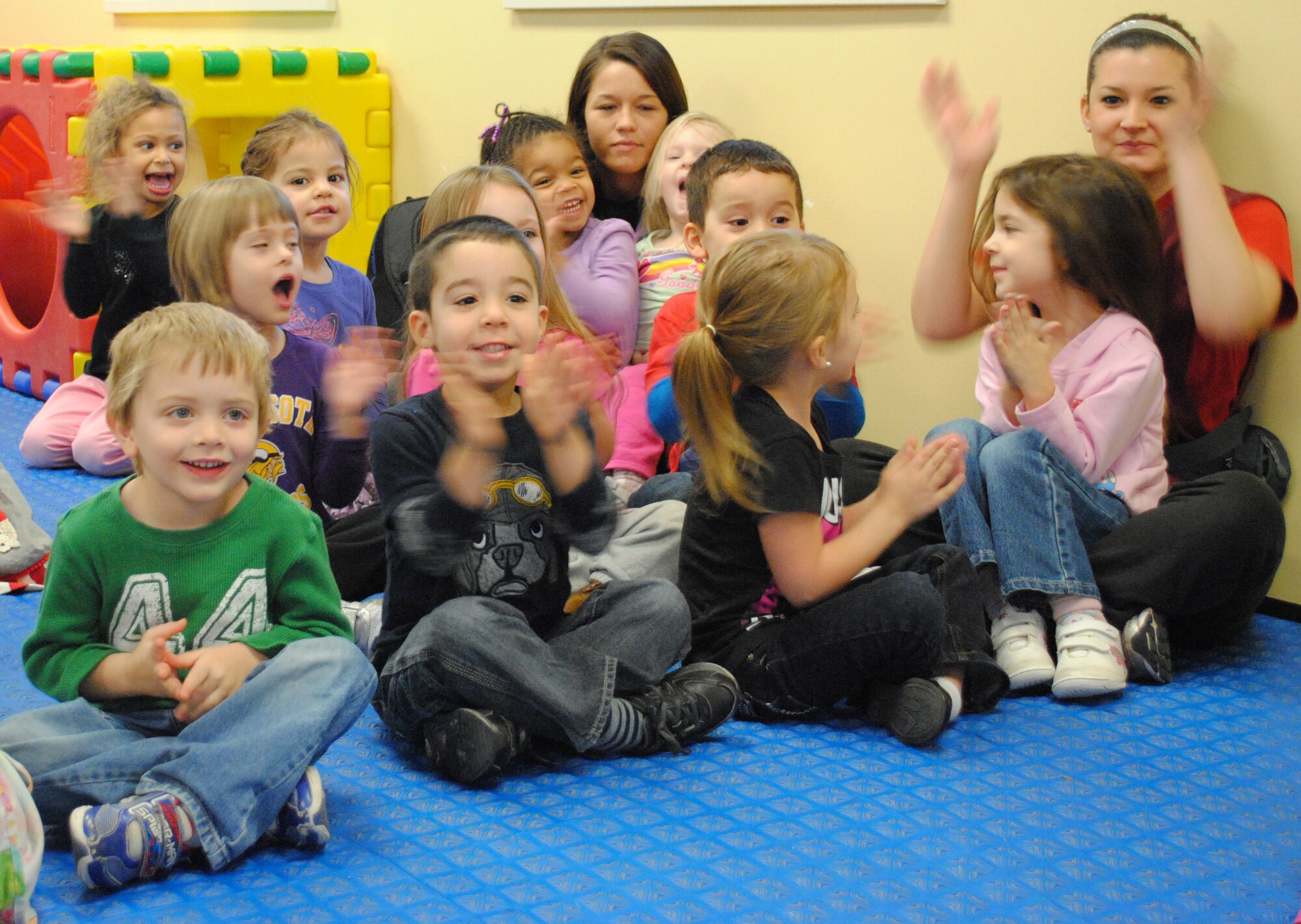 Child care providers and military youngsters show their appreciation by clapping  for members of the United States Air Force Heartland of America Band, who’d just finish playing “Rudolph the Red-nosed Reindeer,” Dec. 18, 2012, at the Child Development Center on Grand Forks Air Force Base, N.D. The band toured the base for two consecutive days, performing holiday songs at 22 locations around the base. (U.S. Air Force photo/Senior Airman Luis Loza Gutierrez)