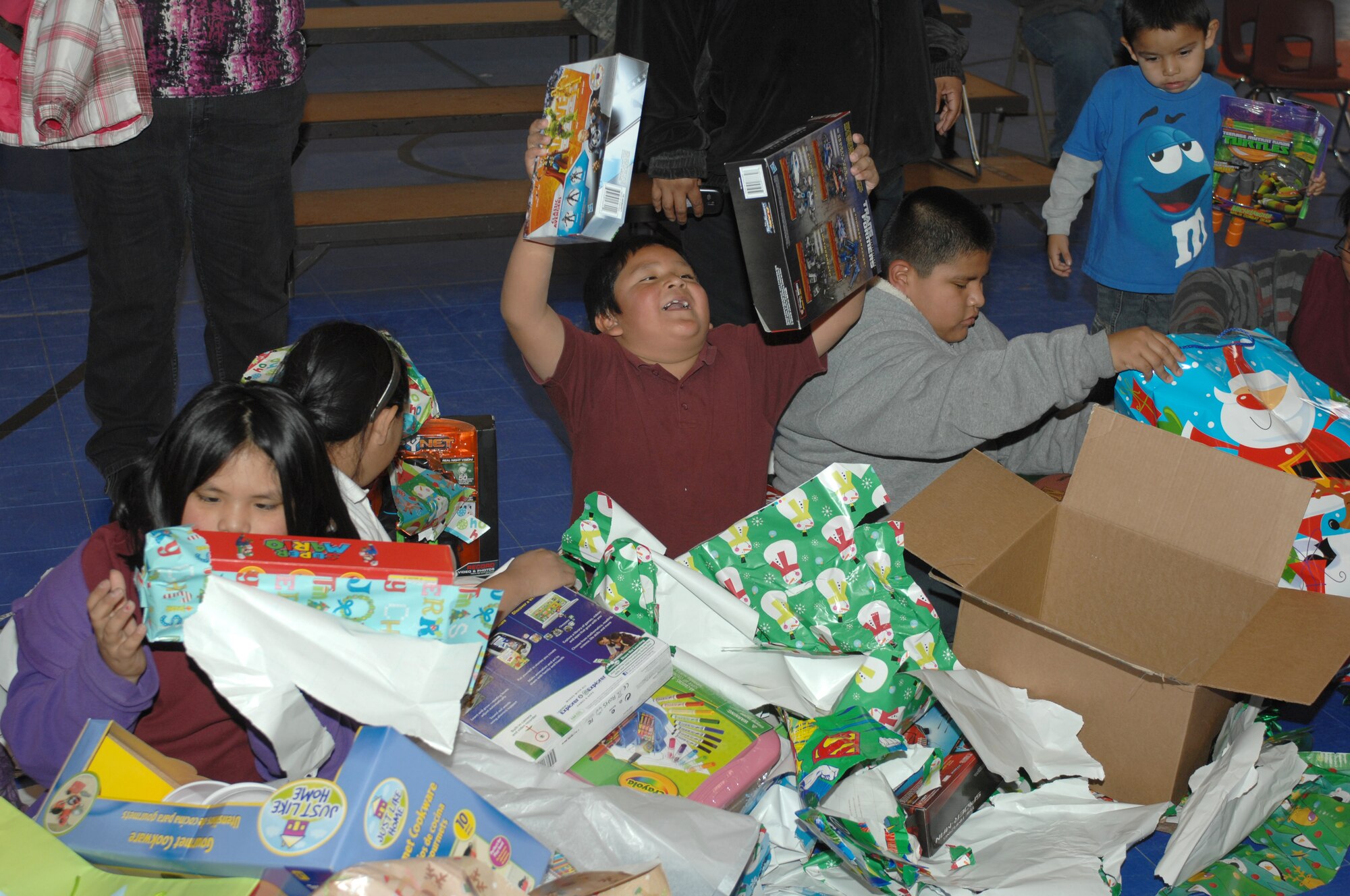 Children from Mrs. Deborah Cannon’s second grade class unwrap their presents during the Santa’s in Blue event at Indian Oasis Elementary School in Sells, Ariz., Dec. 20. Each class was brought in one at a time to receive their presents and find out what they got. (U.S. Air Force photo by Senior Airman Michael Washburn/Released)