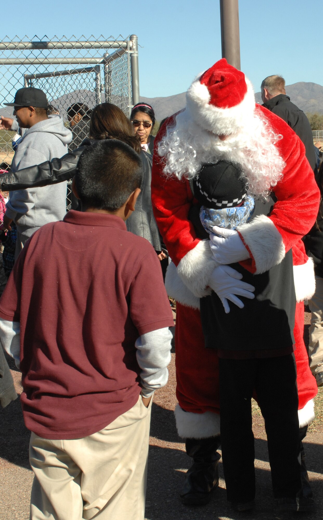 Santa hugs a child from Indian Oasis Elementary School after arriving by helicopter for the Santa’s in Blue event at Sells, Ariz., Dec. 20. Santa’s in Blue was held at Indian Oasis Elementary School and also San Xavier Mission School. (U.S. Air Force photo by Senior Airman Michael Washburn/Released)