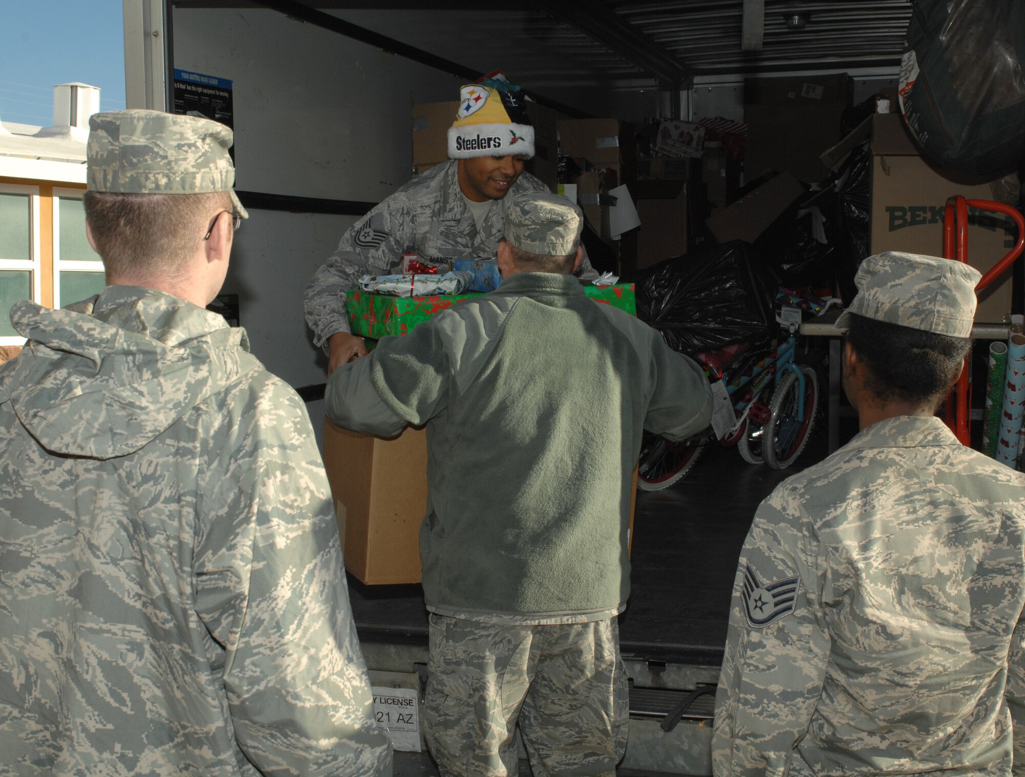 U.S. Air Force Tech Sgt. David Manso, 612th Air Communications Squadron, hands a box of presents to an Airman during the Santa’s in Blue event at Indian Oasis Elementary School in Sells, Ariz., Dec. 20. The presents were either taken to the library or the gym for the different classes of children. (U.S. Air Force photo by Senior Airman Michael Washburn/Released)