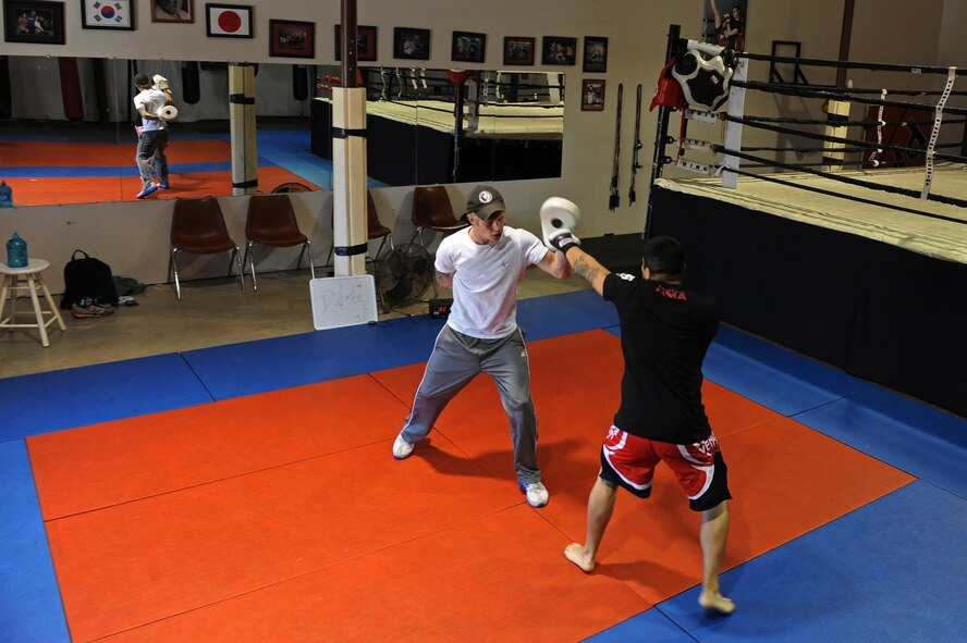 Staff Sgt. Jeremy Caudillo, 2nd Force Support Squadron, spars with Russell Biggs, mixed martial arts general manager and trainer, at a local MMA gym in Bossier City, La., Dec. 12. Caudillo started competing in local amateur MMA fights after his deployment to Afghanistan. Over the years Caudillo learned kick boxing, Jiu-Jitsu and Muay Thai along with various strength and endurance exercises. (U.S. Air Force photo/Senior Airman Micaiah Anthony)