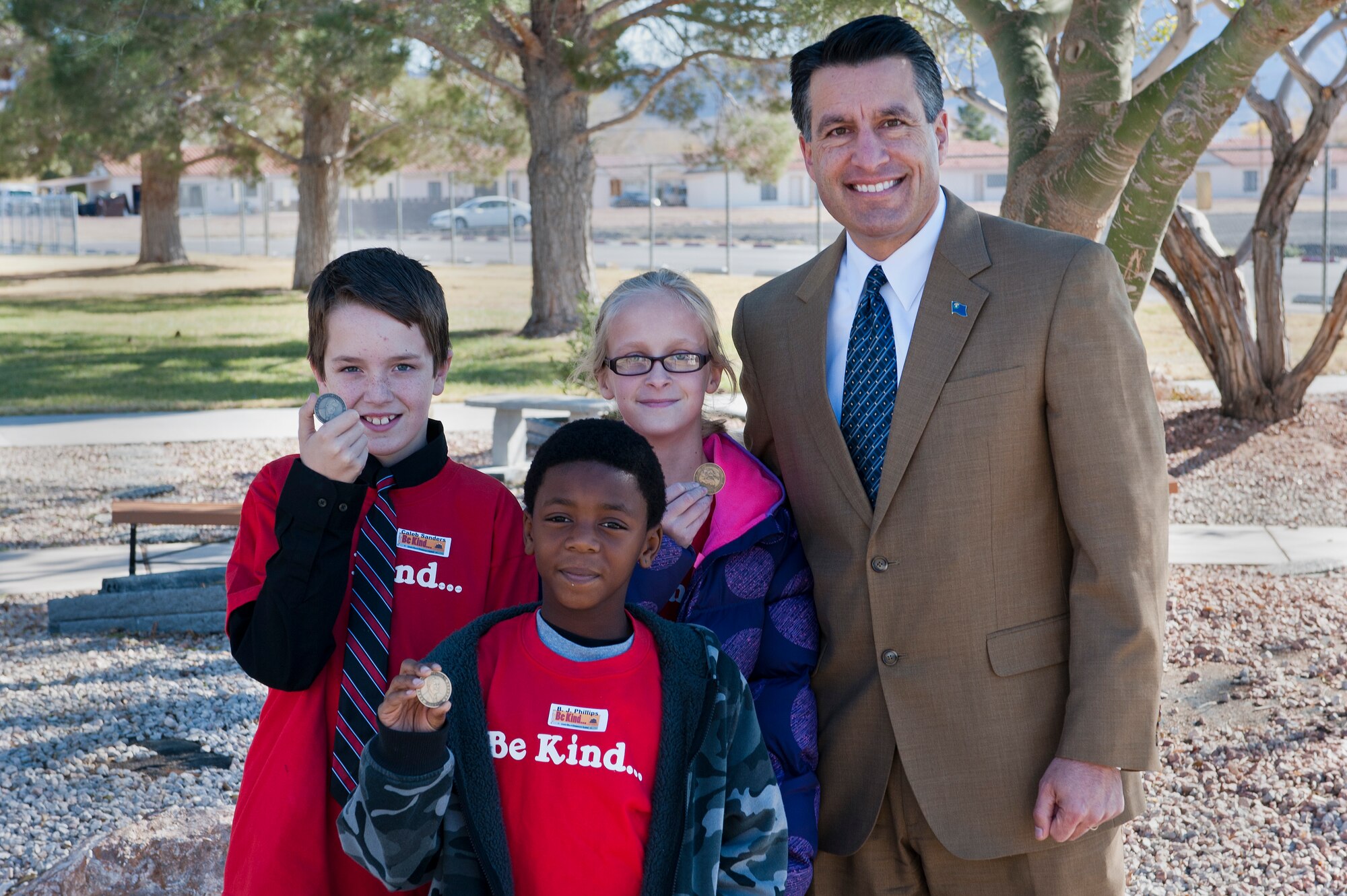 Caleb Sanders, Karlee Brennan, and B.J. Phillips show off their coins that Nevada Governor Brian Sandoval gave to them upon arriving at Lomie Heard Elementary School Dec. 19th, 2012, at Nellis Air Force Base, Nev. Sandoval and his wife Kathleen are program directors for the Children's Cabinet in Reno, Nev. One of the services that the Children’s Cabinet offers is academic support and tutoring. (U.S. Air Force Photo by Airman 1st Class Jason Couillard)
