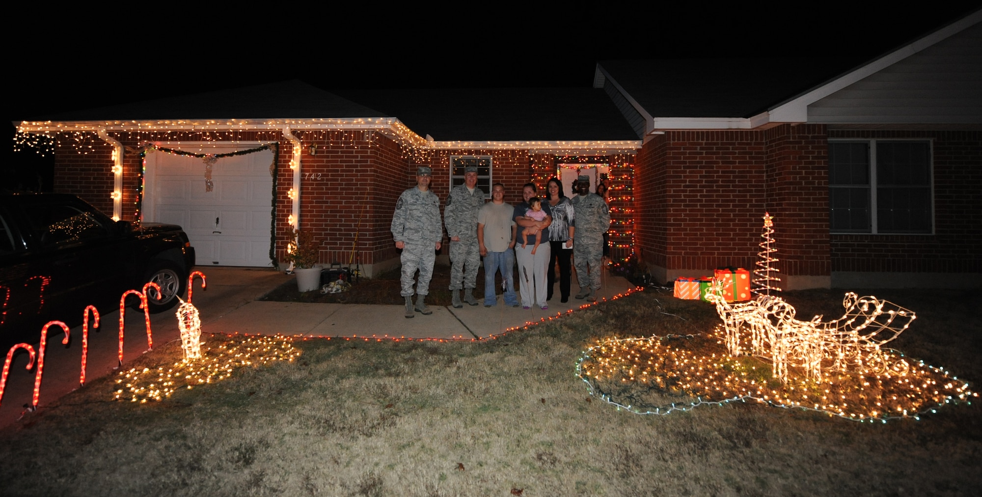 A winner of the holiday lighting contest poses with members of the Barksdale Chief's Group and a representative from the housing office during the Holiday Lights Contest on Barksdale Air Force Base, La., Dec. 18. Four houses were chosen as having the best holiday decorations and were presented with a $100 gift card. (U.S. Air Force photo/Senior Airman Sean Martin)