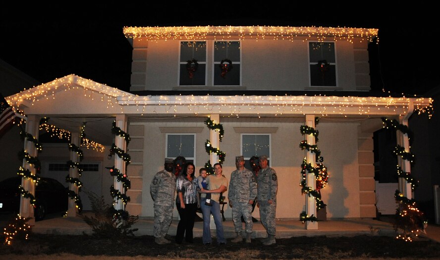 A winner of the holiday lighting contest poses with members of the Barksdale Chief's Group and a representative from the housing office during the Holiday Lights Contest on Barksdale Air Force Base, La., Dec. 18. Four houses were chosen as having the best holiday decorations and were presented with a $100 gift card. (U.S. Air Force photo/Senior Airman Sean Martin)