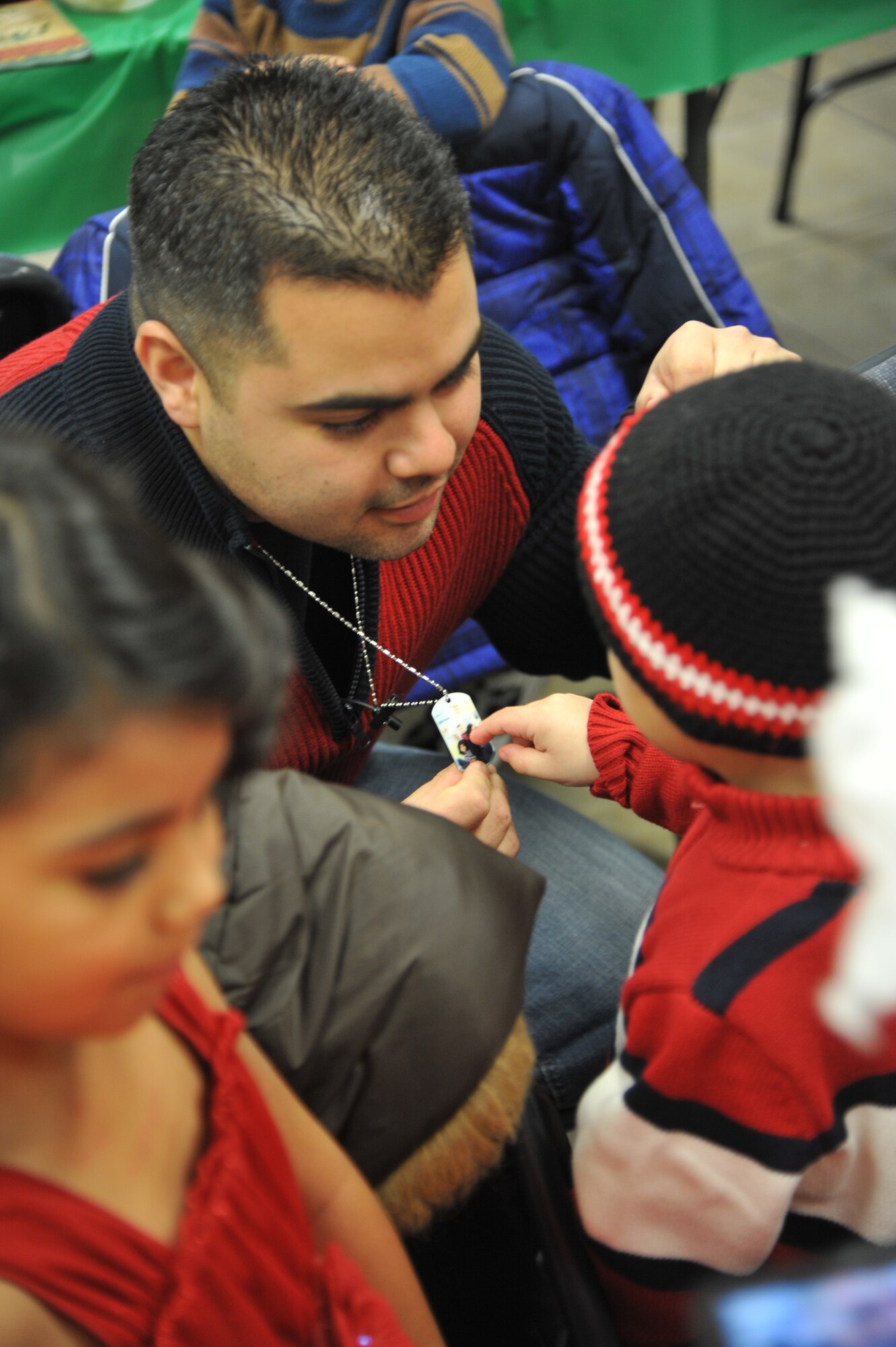Staff Sgt. Eduardo Madera-Muniz, 8th Aircraft Maintenance Unit, shows his son Ezekiel Madera, 3, a dog-tag with a photo of the family Dec. 13 after surprising his children by arriving unannounced at the deployed spouse’s dinner.  (U.S. Air Force photo/Senior Airman Sandra Welch)