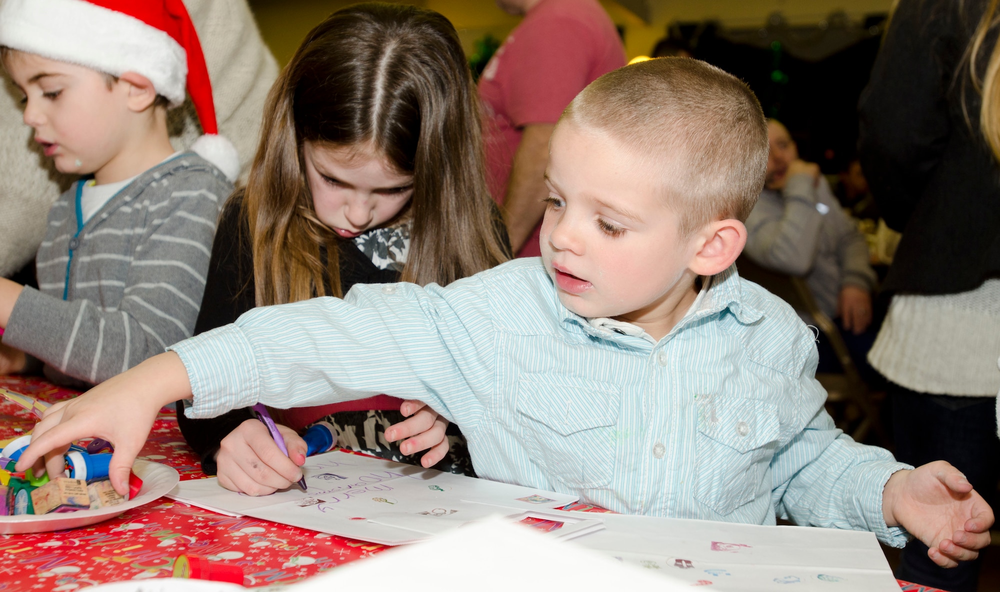 MILDENHALL, England - Lennon, 5, reaches for a stamp while working on Christmas crafts during the 48th Equipment Maintenance Squadron Annual Christmas Party, which was held for U.K. children at the Jubilee Center Dec. 17, 2012. The event, which 48th EMS Airmen have been putting on for 15 years, maintains traditions stemming from World War II when Americans would hold parties and give gifts to local children. (U.S. Air Force photo by Staff Sgt. Stephen Linch)