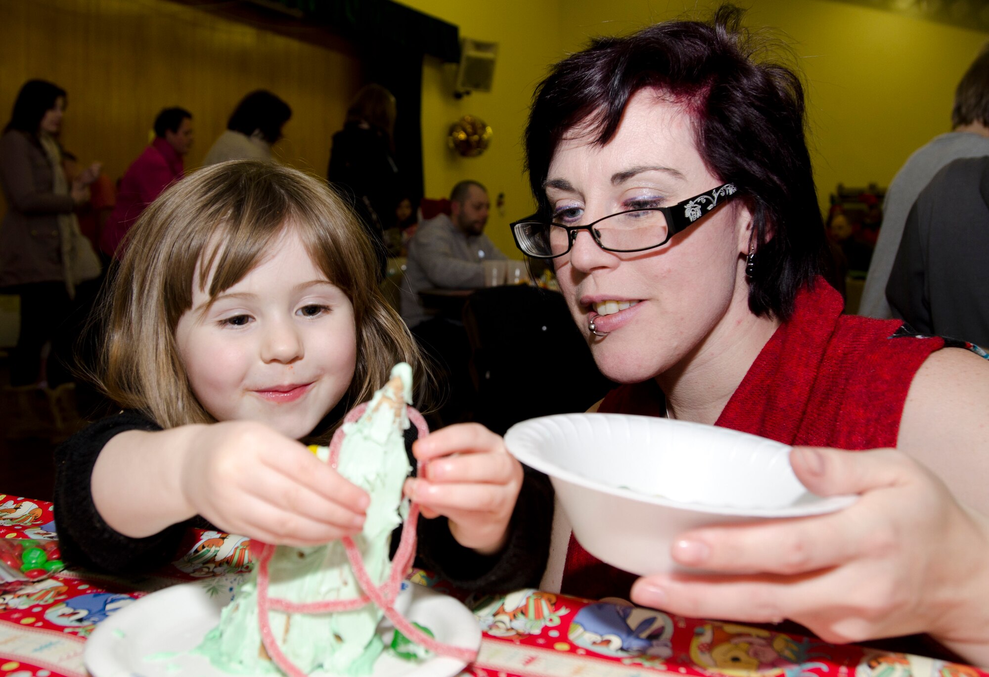 MILDENHALL, England - Heather, 3, works on her candy Christmas tree with her mom, Jen, during the 48th Equipment Maintenance Squadron Annual Christmas Party, which was held for U.K. children at the Jubilee Center Dec. 17, 2012. The event, which 48th EMS Airmen have been putting on for 15 years, maintains the traditions stemming from World War II when Americans would hold parties and give gifts to local children. (U.S. Air Force photo by Staff Sgt. Stephen Linch)
