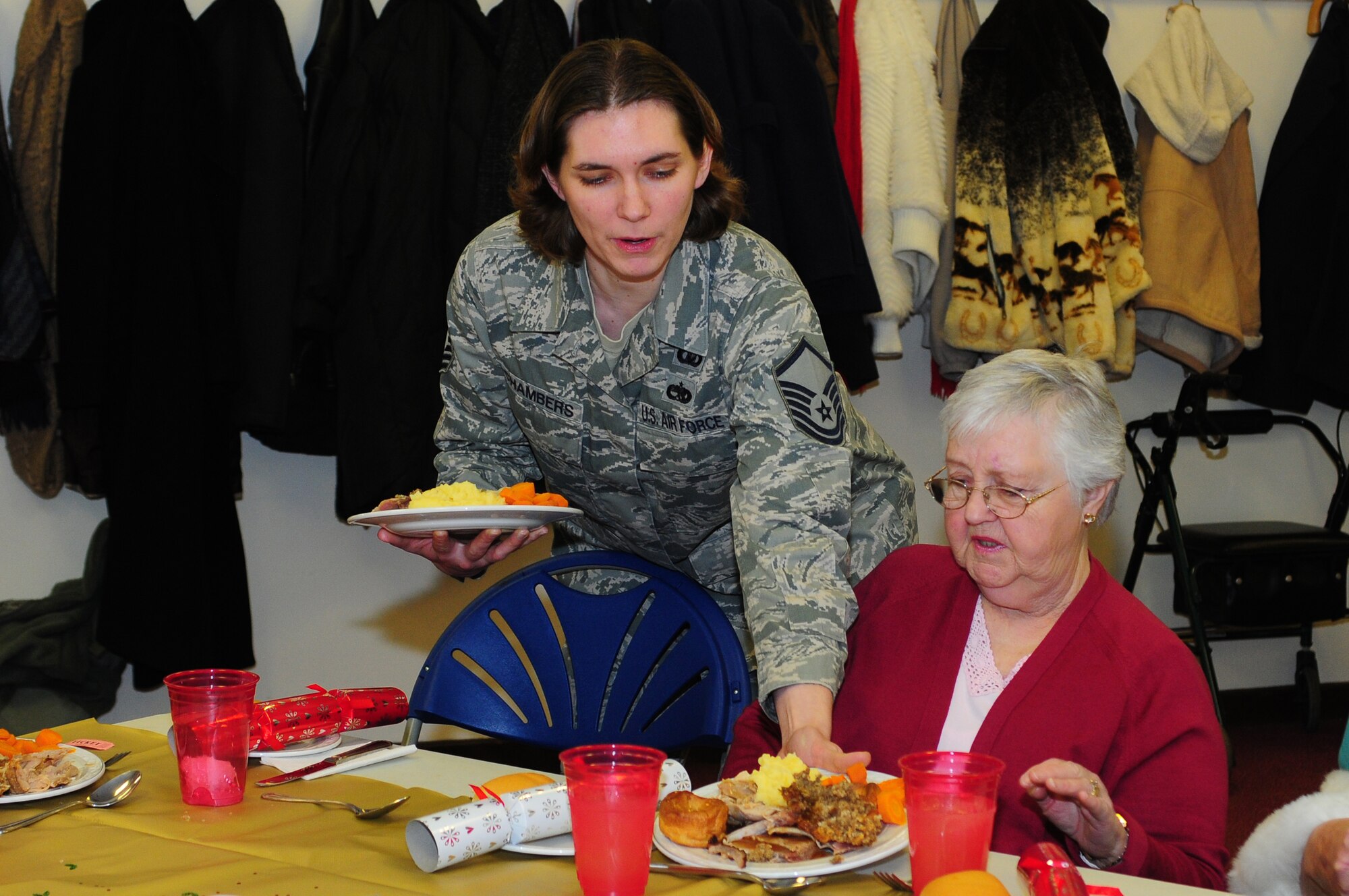 ROYAL AIR FORCE LAKENHEATH, England – Master Sgt. Sadie Chambers, 48th Fighter Wing chaplain operations superintendant, delivers food to Marion Maynard, of Mildenhall Village, during a Christmas lunch hosted by the 48th Security Forces Squadron Dec. 19, 2012. More than 40 members of the local community attended the luncheon which included games, prizes and holiday gifts donated by Liberty Wing Airmen. (U.S. Air Force photo by Airman 1st Class Cory D. Payne)
