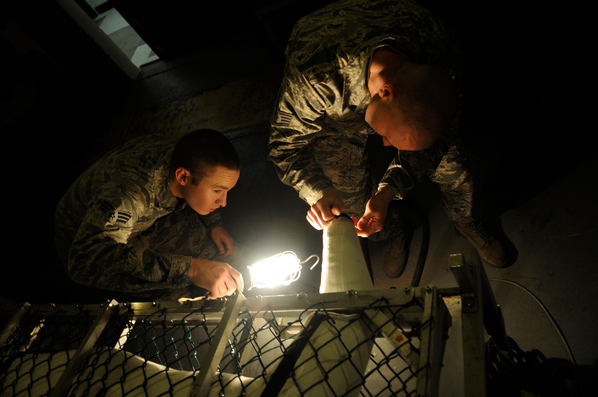 Senior Airman Joshua Stewart, left, 8th Operations Support Squadron aircrew flight equipment technician, illuminates the wrist seal of an anti-exposure suit as Staff Sgt. Joshua Smith, 8th OSS AFE assistant NCO in charge, seals it during water testing Dec. 11, 2012, at Kunsan Air Base, Republic of Korea. The suits increase the chances of a pilot’s survival if he must eject over water during a flight. (U.S. Air Force photo by Senior Airman Brigitte N. Brantley/Released)