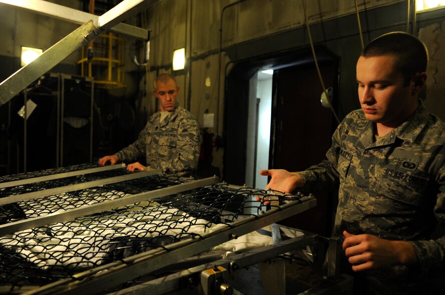 Staff Sgt. Joshua Smith, left, 8th Operations Support Squadron aircrew flight equipment assistant NCO in charge, and Senior Airman Joshua Stewart, 8th OSS AFE technician, prepare to water test an anti-exposure suit Dec. 11, 2012, at Kunsan Air Base, Republic of Korea. The AFE technicians turn the suit inside out and fill it with water before thoroughly inspecting it for any leaks. (U.S. Air Force photo by Senior Airman Brigitte N. Brantley/Released)