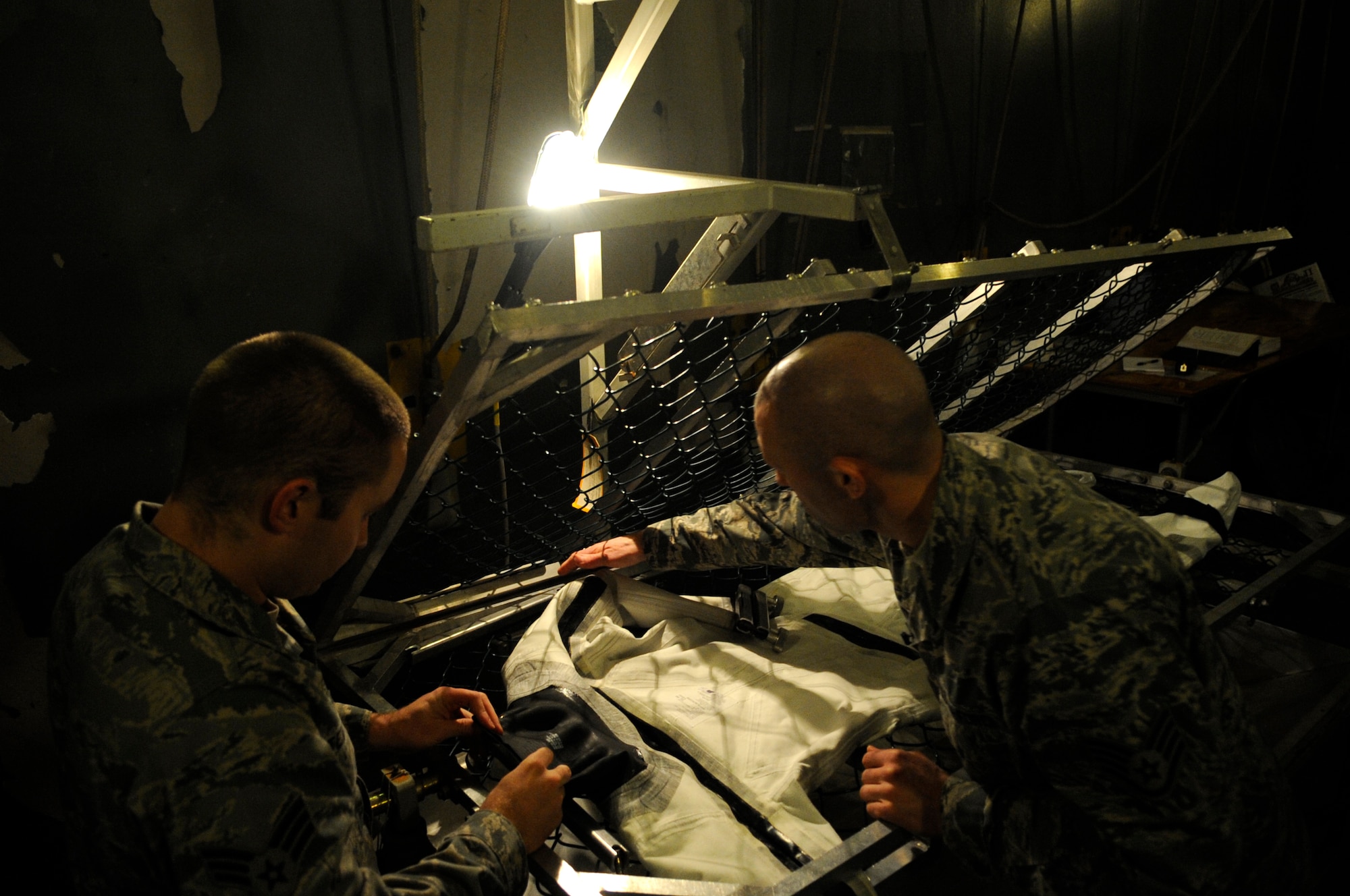 Staff Sgt. Joshua Smith, right, 8th Operations Support Squadron aircrew flight equipment assistant NCO in charge, and  Senior Airman Joshua Stewart, 8th OSS AFE technician, prepare an anti-exposure suit for water testing Dec. 11, 2012, at Kunsan Air Base, Republic of Korea. The suits are worn by pilots when water temperatures fall below 60 F. (U.S. Air Force photo by Senior Airman Brigitte N. Brantley/Released)