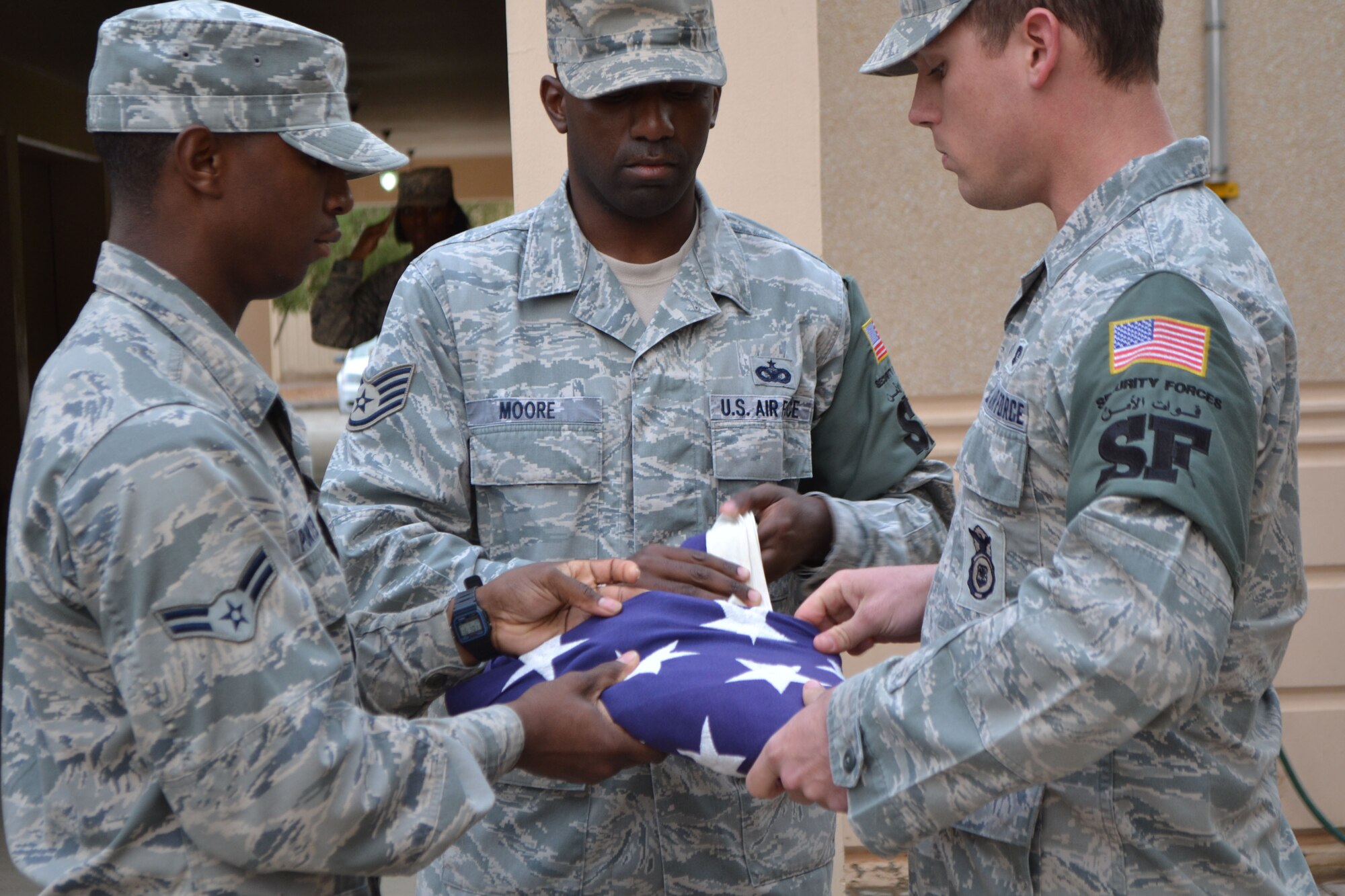 SOUTHWEST ASIA - (Left to right) Airman 1st Class Tyree Porter, Staff Sgt. Jason Moore and Senior Airman Anthony Scharf fold the American flag during a retreat ceremony recently. The Airmen are assigned to the 64th Air Expeditionary Group and were part of a team that performed reveille and retreat ceremonies daily during the month of November. (U.S. Air Force photo/Staff Sgt. Cynthia Brockes)
