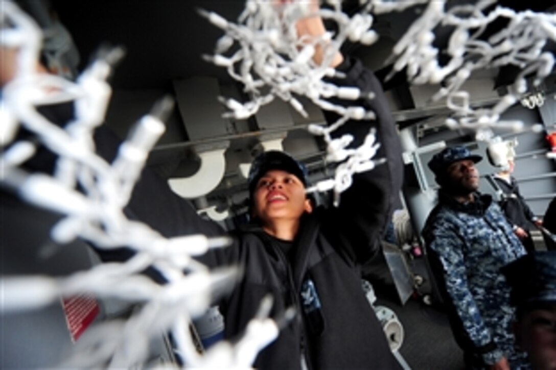 U.S. Navy Petty Officer 3rd Class Carrel Regis hangs holiday lights on the officers' quarterdeck aboard the aircraft carrier the USS George H.W. Bush in Norfolk, Va., Dec. 12, 2012.