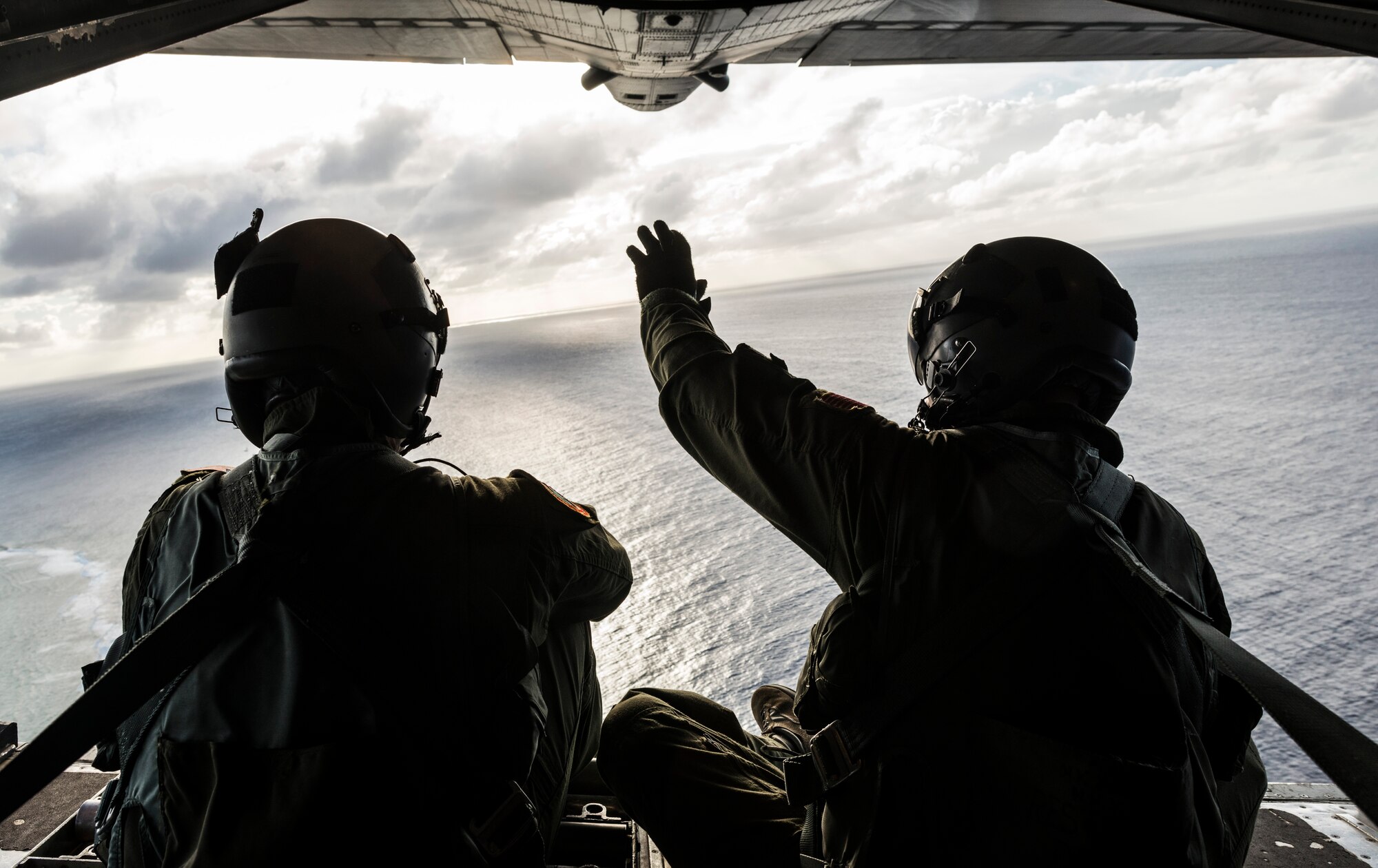OVER MICRONESIA -- Senior Airman Timothy Oberman, left, and Staff Sgt. Nick Alarcon, loadmasters with the 36th Airlift Squadron, Yokota Air Base, Japan, waive out the back of a C-130H aircraft after dropping the first pallet of humanitarian goods to the island of Ulal Dec. 11, 2012. Operation Christmas Drop is a non-profit organization powered by volunteers from Andersen Air Force Base and the local Guam community. Each year Operation Christmas Drop provides aid to over 30,000 islanders in Chuuk, Palau, Yap, Marshall Islands and Commonwealth of the Northern Mariana Islands. This year is the 61st anniversary of Operation Christmas Drop, making it the longest running humanitarian mission in the world. (U.S. Air Force photo by Tech. Sgt. Samuel Morse)
