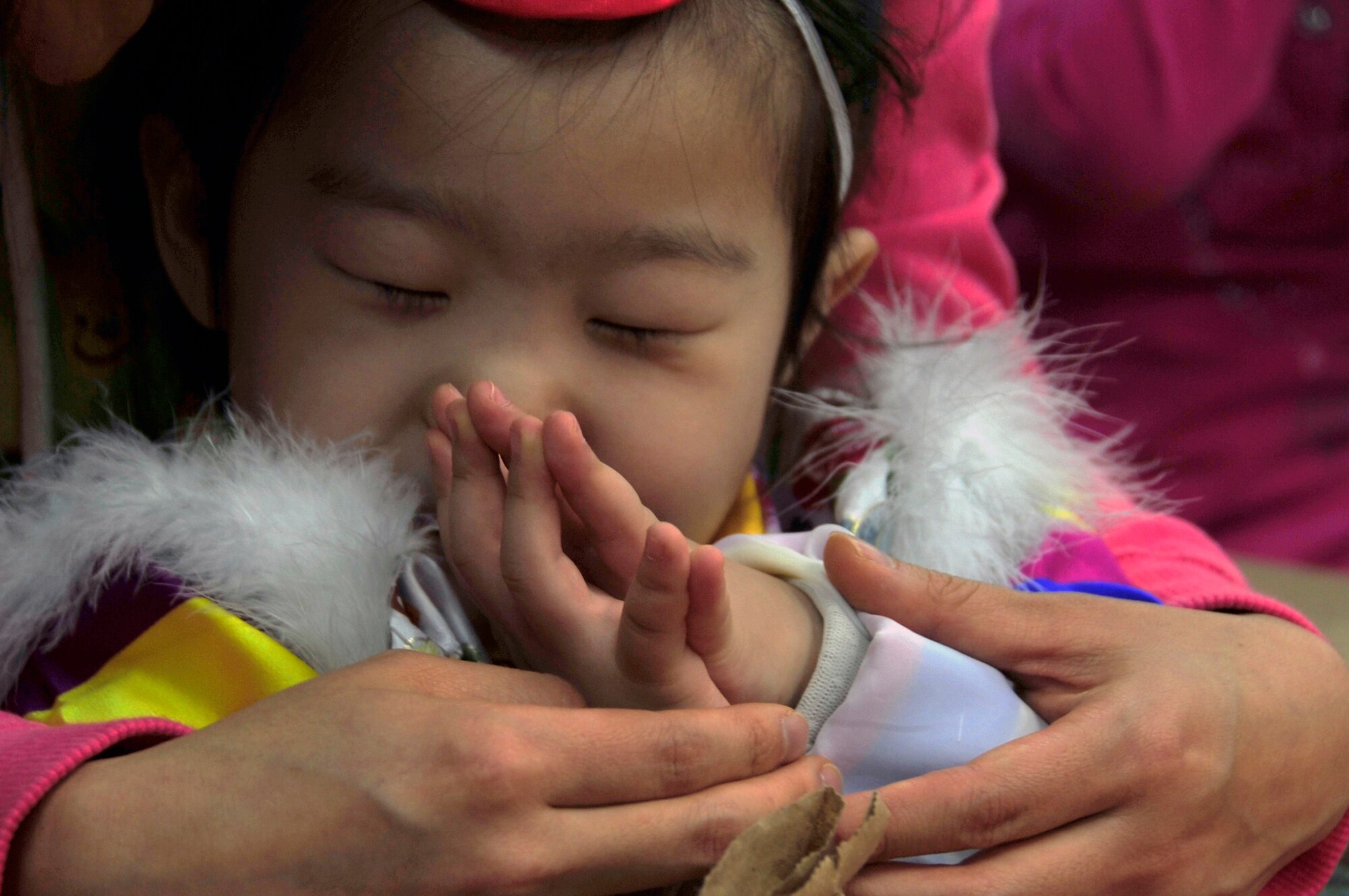 A Korean orphan folds her hands in prayer during a visit to an orphanage through Operation Christmas Hope Dec. 22, 2012. More than 600 volunteers from the base community came together to deliver the gifts, sing Christmas carols and offer prayer at local Korean orphanages. (U.S. Air Force photo/Airman 1st Class Alexis Siekert)
