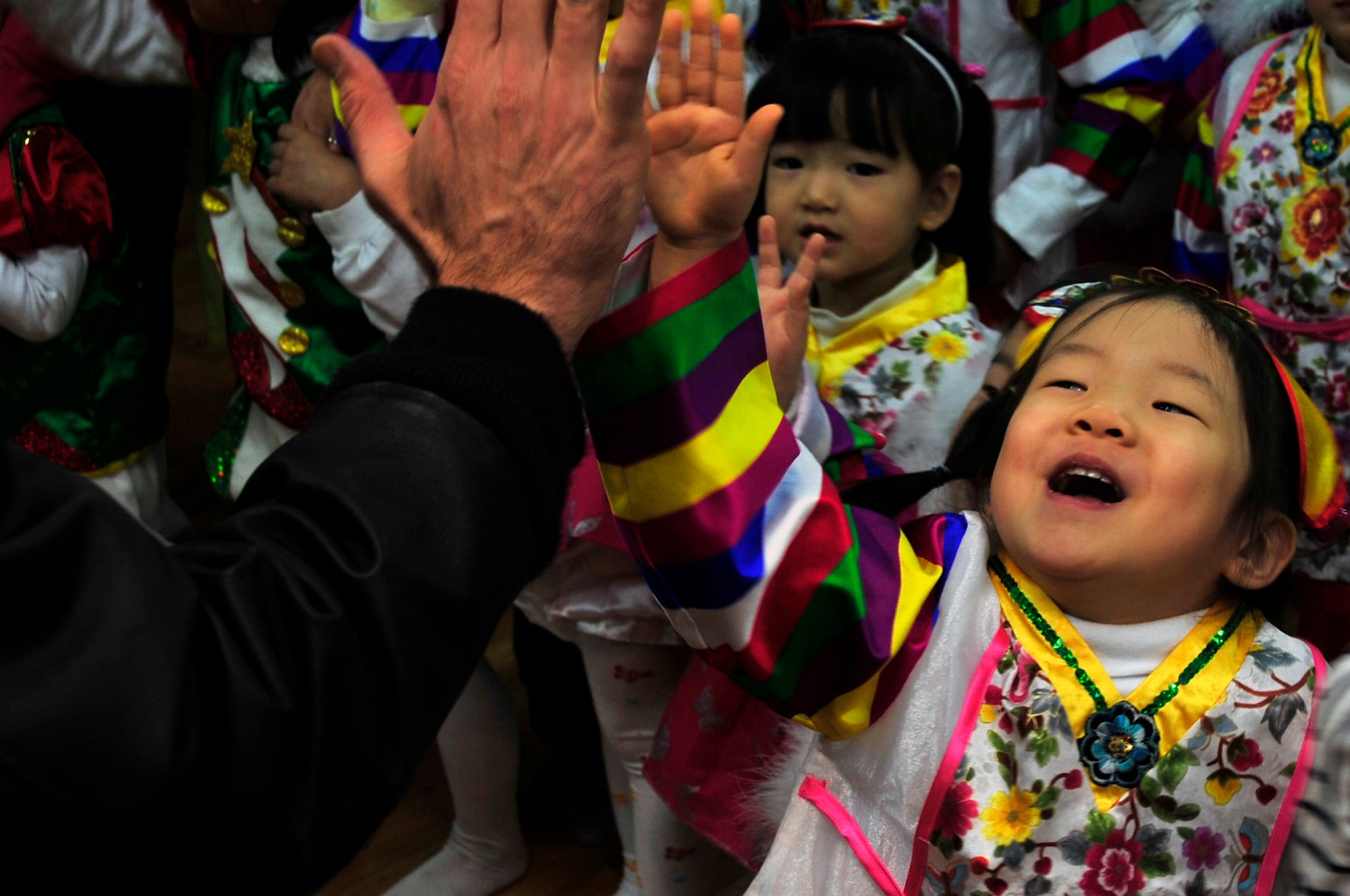 Korean orphans high-five Team Osan volunteers at an orphanage Dec. 22, 2012. Volunteers met with more than 2,000 orphans to spread some holiday cheer. (U.S. Air Force photo/Airman 1st Class Alexis Siekert)