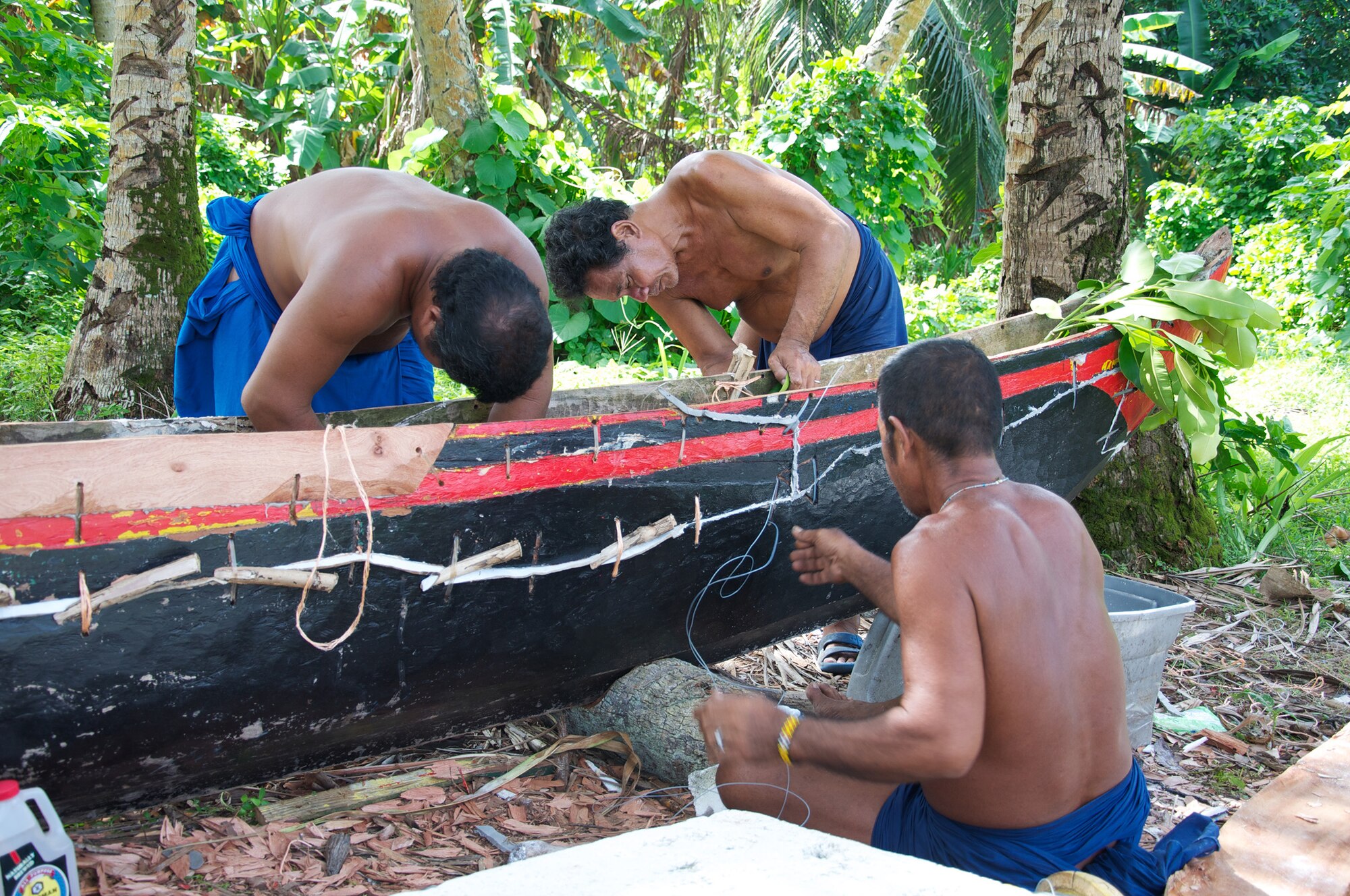 Islanders repair a boat near the island of Falalop, Micronesia, in 2011. They use a compound made by dissolving styrofoam in gasoline, which creates a paste which they say is very effective at waterproofing boats. (Courtesy photo by Master Sgt. Cameron Leslie)