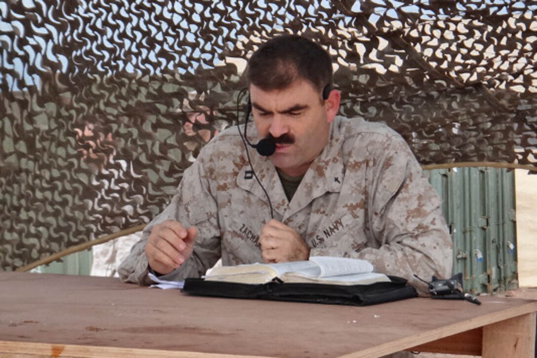 Lieutenant Stephen J. Zachary, chaplain, Combat Logistics Battalion 15, 15th Marine Expeditionary Unit, pauses during a training exercise the unit was conducting in the U.S. 5th Fleet area of responsibility, Dec. 17, to read encouraging scripture at a memorial service for the victims and loved ones of the Newtown, Conn., shooting. Members of the battalion took a break from their daily training and operating schedule to mourn for those affected by the Sandy Hook Elementary shooting. After a moment of silence, underneath camouflaged netting, the chaplain read scripture of encouragement and said prayers for those lost during the heartbreak. The 15th MEU is deployed as part of the Peleliu Amphibious Ready Group as a U.S. Central Command theater reserve force, providing support for maritime security operations and theater security cooperation efforts in the U.S. 5th Fleet area of responsibility. (Courtesy photo)